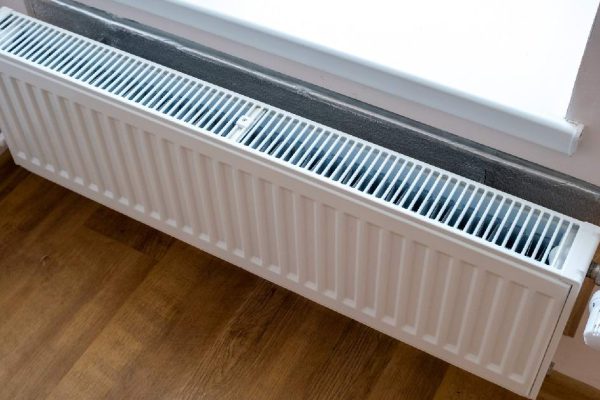 White metal heating radiator mounted on a wall in room interior.