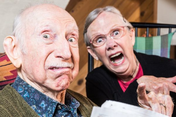 Old mad couple reading a newspaper in their living-room