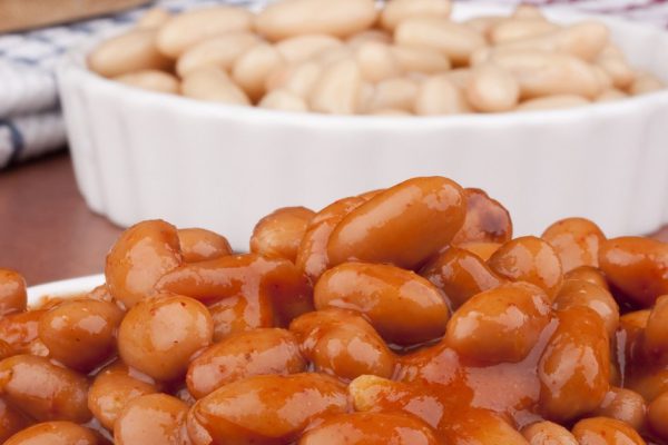 White canned beans in a white ceramic dish with red sauce.