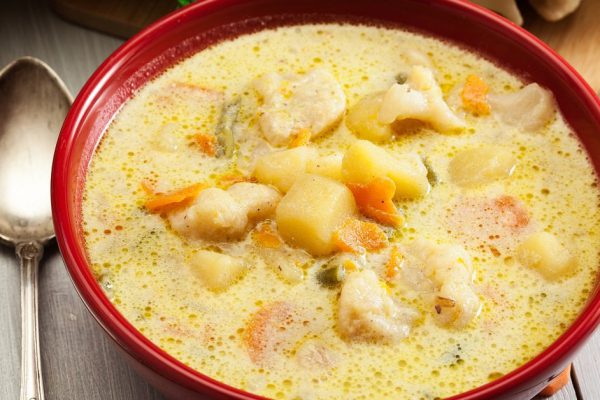 Vegetable soup with ingredients carrot, cauliflower, potato and parsley in red bowl