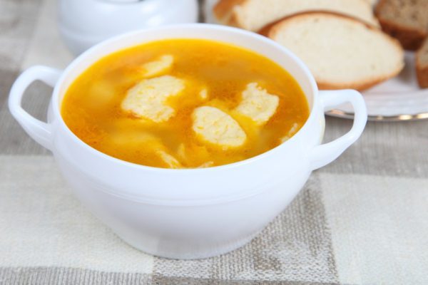 Soup with dumplings in a white plate on the table