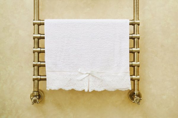 Modern heated towel rail on  bathroom wall.