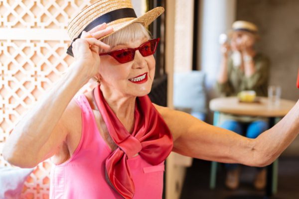Stylish look. Positive aged woman fixing her sunglasses while taking selfies
