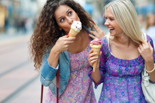 two teen woman friends having fun and eating ice cream