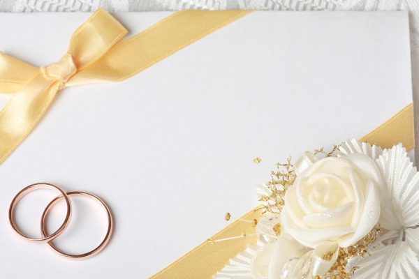 Wedding invitation card with gold rings and satin rose