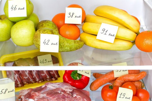 Open fridge full of fruits, vegetables and meat with marked calories
