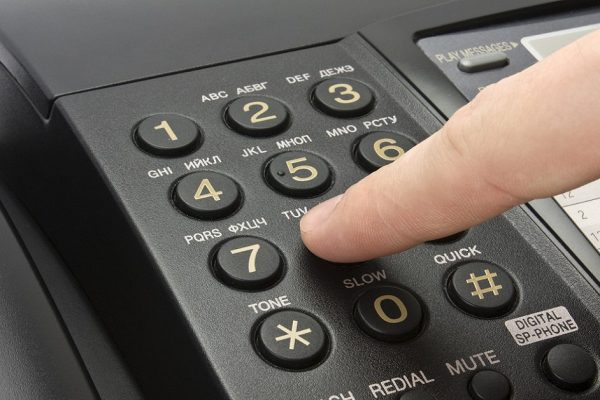 hand pressing key on black phone