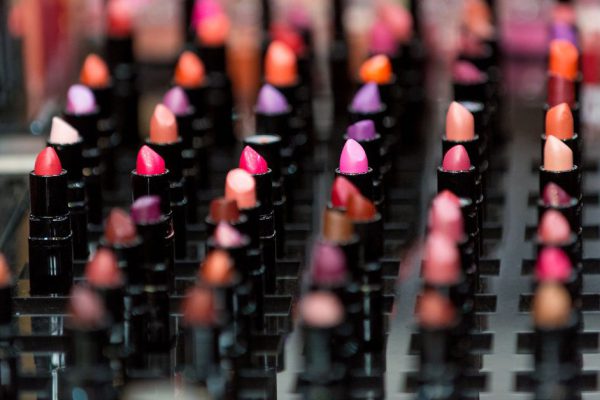 Beautiful big multicolor professional makeup set of many different colorful lipsticks in black plastic tubes in show case, horizontal picture