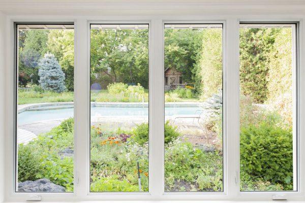 Large four pane window looking on summer backyard with pool and garden