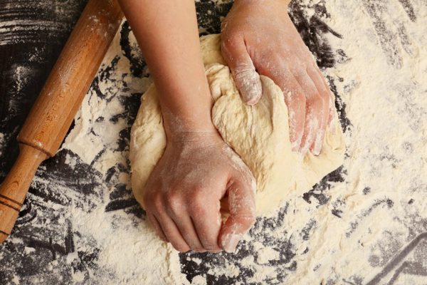 Making dough by female hands on wooden table background
