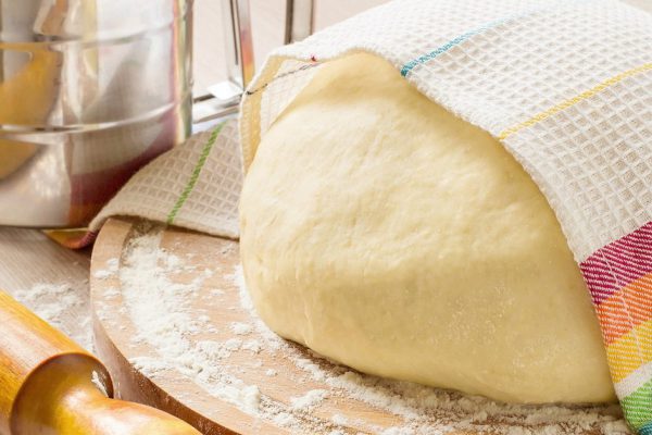 Special yeast dough for making braided cakes, pies and rolls on a round board with a towel. During preparation the heat is eliminated, getting ready in the refrigerator