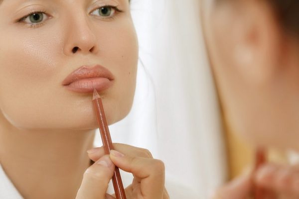 Woman drawing lip contour with a pencil