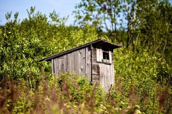 old country toilet waiting to be used in high grass