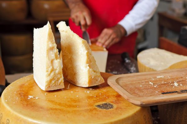 Two pieces of cheese on top of whole Parmesan wheel at International Cheese Festival in Bra, Northern Italy.