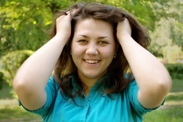 The young laughing girl outdoors, with a voluminous hair