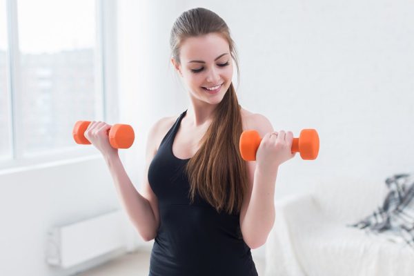 Active sportive athletic woman with dumbbells pumping up muscles biceps concept fitness sport training lifestyle