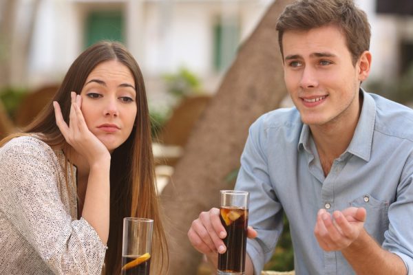 Man and woman dating in a restaurant terrace but she is boring while he speaks