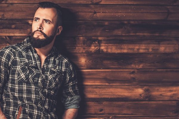 Handsome man wearing checkered  shirt in wooden rural house interior