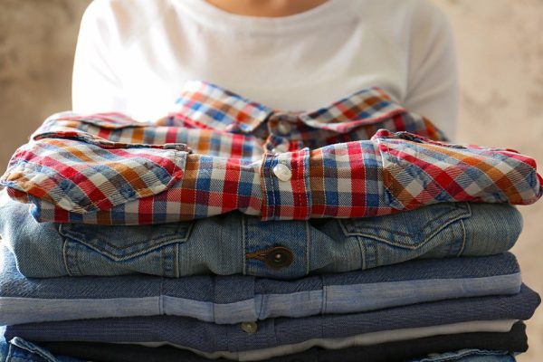 Woman holding folded clothes in hands, closeup