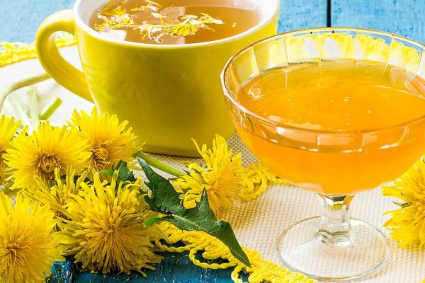 Dandelions, flower tea and jam of dandelions on a blue wooden background. Selective focus