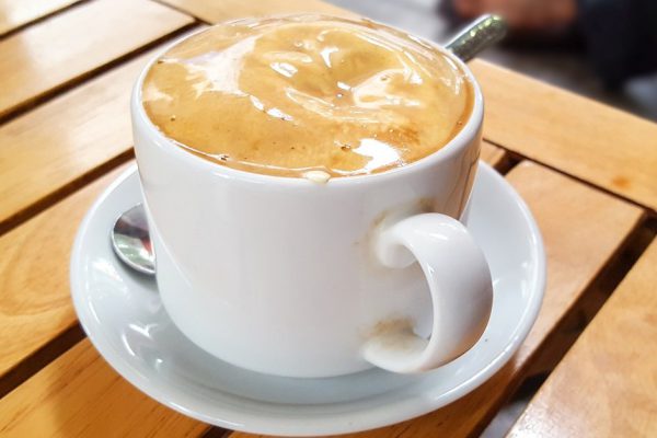 A cup of Vietnamese egg coffee on the wooden table. An egg coffee is a Vietnamese drink which is traditionally coffee