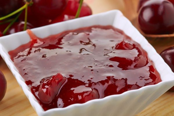 bowl of cherry jam on wooden table