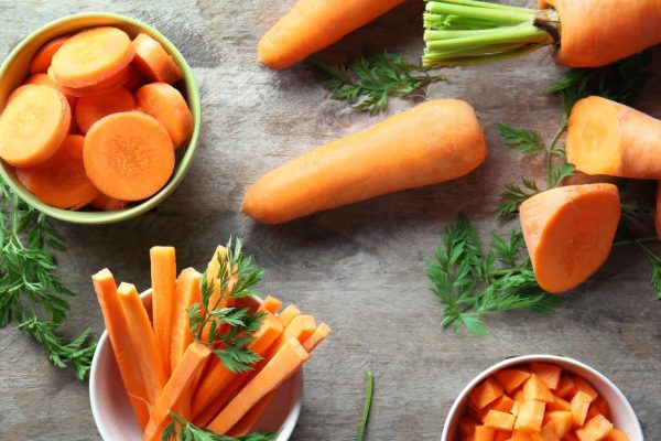 Bowls with cut carrot on table, top view