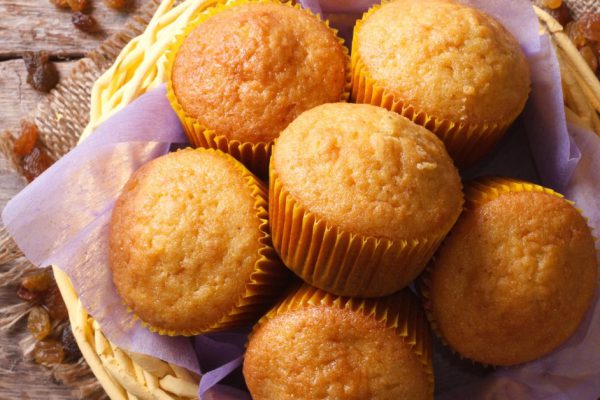 Orange muffins in a basket and raisins on an old table close-up. horizontal view from above