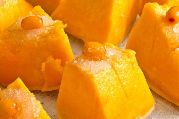 Fresh sliced pumpkin with sea-buckthorn and sugar on top ready to bake.