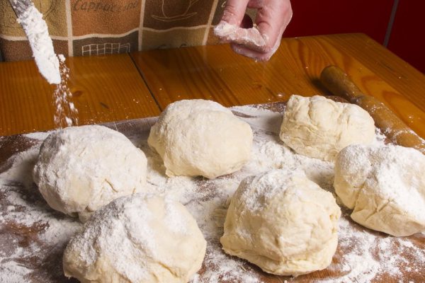Making dough by female hands on wooden table background