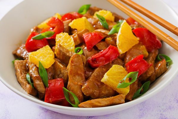 Veal fillet - stir fry with oranges and paprika in sweet and sour sauce on a light background
