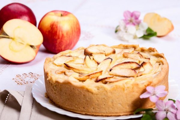 Apple pie slice with pie on background, soft focus