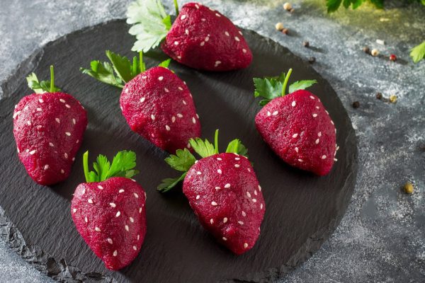Vegan strawberry snack of boiled beets stuffed with herring on a slate board. healthy eating concept.
