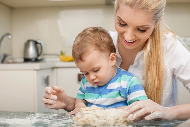 Мама научила сына. Молодая мать с сыном 5 лет на кухне.