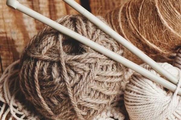 Needlework, macrame, knitting. Yarn and thread of natural colors in a wicker basket. Women's hobby.