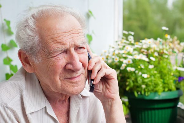 sad, gloomy senior man speaking on the phone with somebody