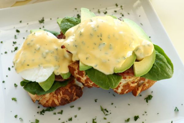 Beautiful eggs benedict with bacon and a rich hollandaise sauce on tiger crust bread.