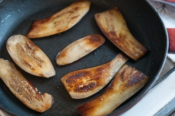 Sliced eggplant on frying pan top view at domestic kitchen
