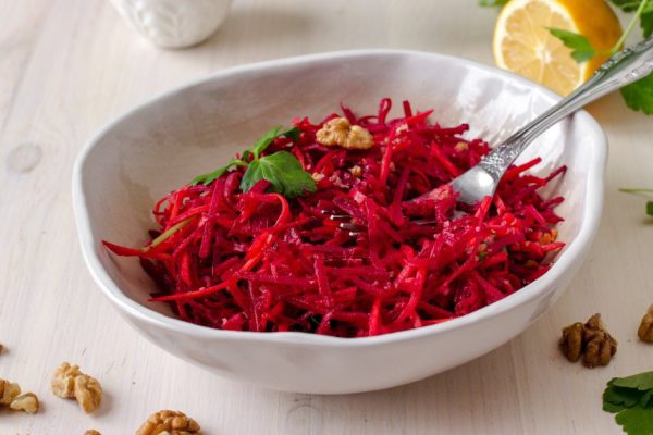 Healthy raw vegan beetroot salad with carrot and walnuts in a bowl on white wooden table. Natural organic food concept. Healthy diet