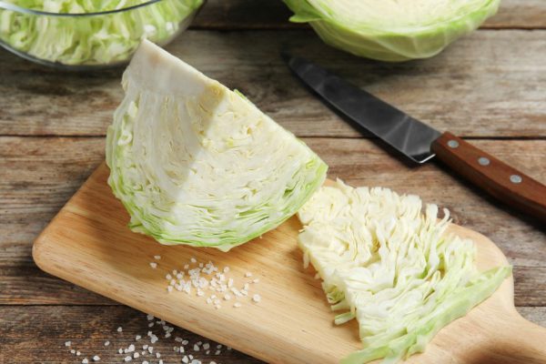 Cutting board with chopped and sliced cabbage on table