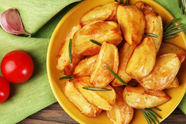 Baked potato wedges on wooden table, top view