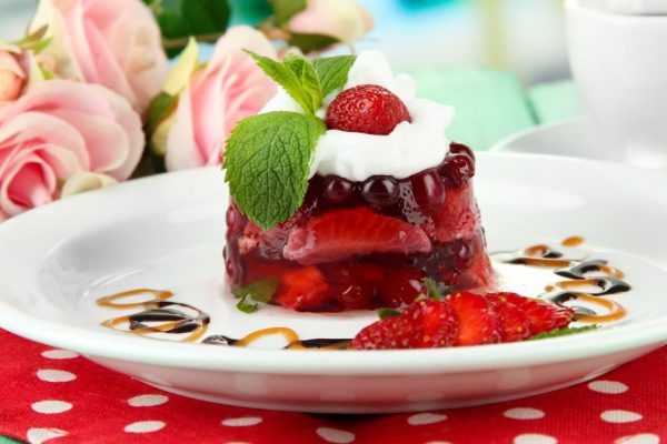 Tasty jelly dessert with fresh berries, on bright background
