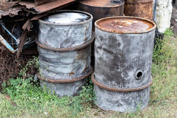 Old barrels for diesel. Metal containers for oil standing on the scrap yard. Season of the autumn.