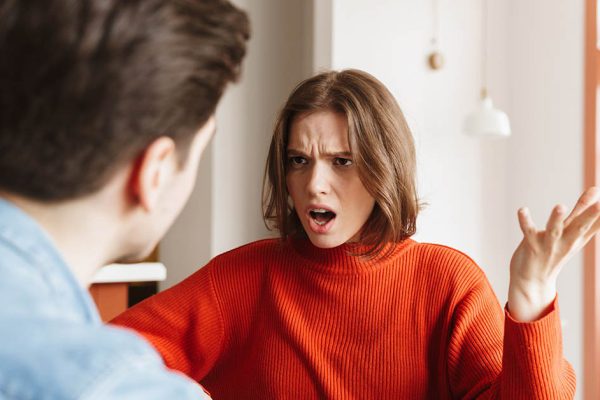 Angry young woman having an argument with her boyfriend at a cafe indoors