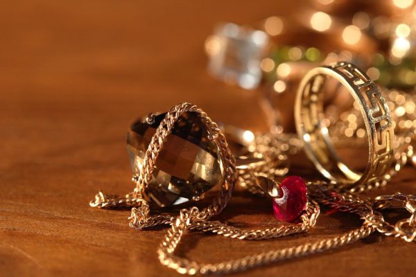 Closeup of pile of gold jewelry on wooden surface with lighting effect