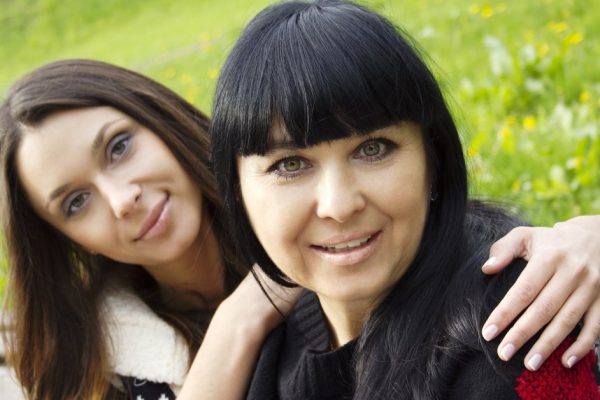 Portrait of smiling mother and teenage daughter hugging in the park happy