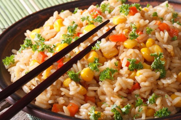 Chinese fried rice with eggs, corn and spices close-up on a plate, horizontal
