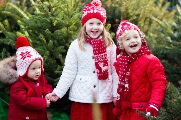 Family selecting Christmas tree. Kids choosing freshly cut Norway Xmas tree at outdoor lot. Children buying gifts at winter fair. Boy and girl shopping for Christmas decoration at market. Holiday time