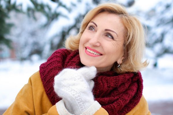 Portrait of happy mature woman in snowy park on winter vacation