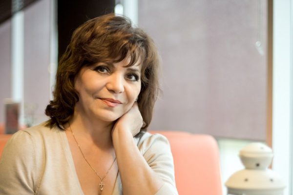 Very beautiful, mature woman, sit in  Cafe and drink coffee, horizontal portrait